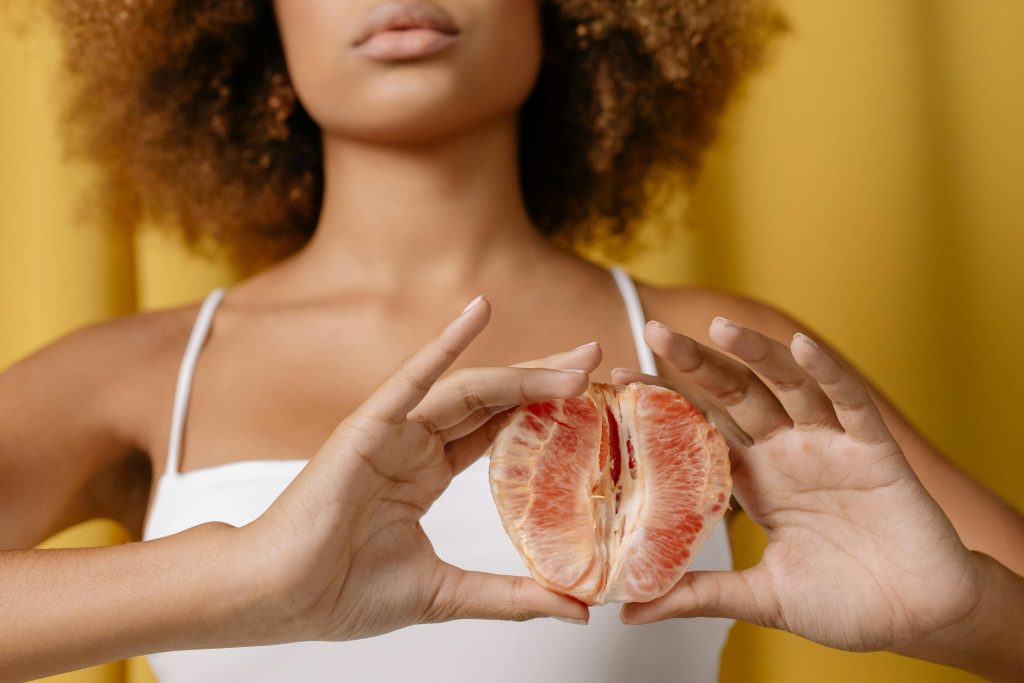 A woman in a white top holding a grapefruit, focused on healthy lifestyle.