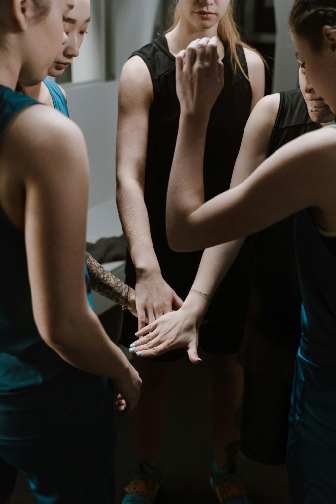 Group of female athletes huddling for motivation before a game indoors.